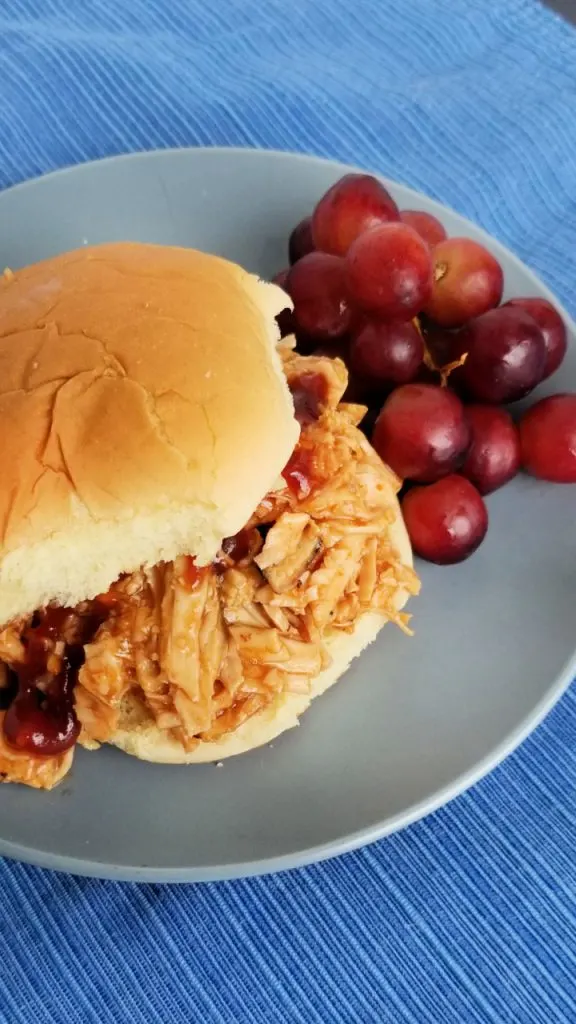A sandwich with slow cooker bbq chicken with grapes on a plate. 