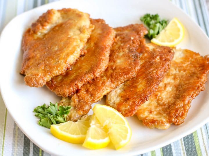 simple breaded pork chops on a plate with lemon wedges