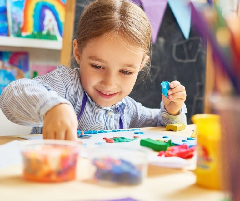 Kids doing crafts at a table full of supplies.