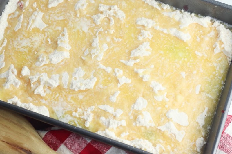 Butter and cake mix on top of berry pie filling in baking pan