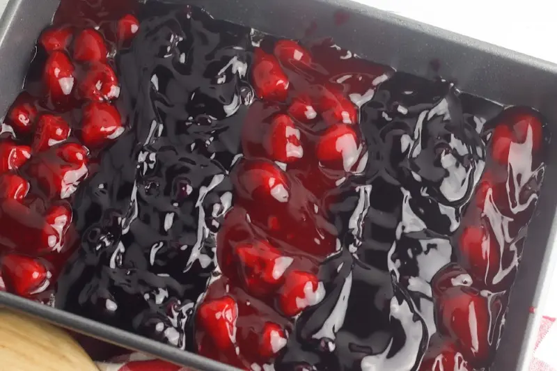 Rows of strawberry and blueberry pie filling in a baking pan