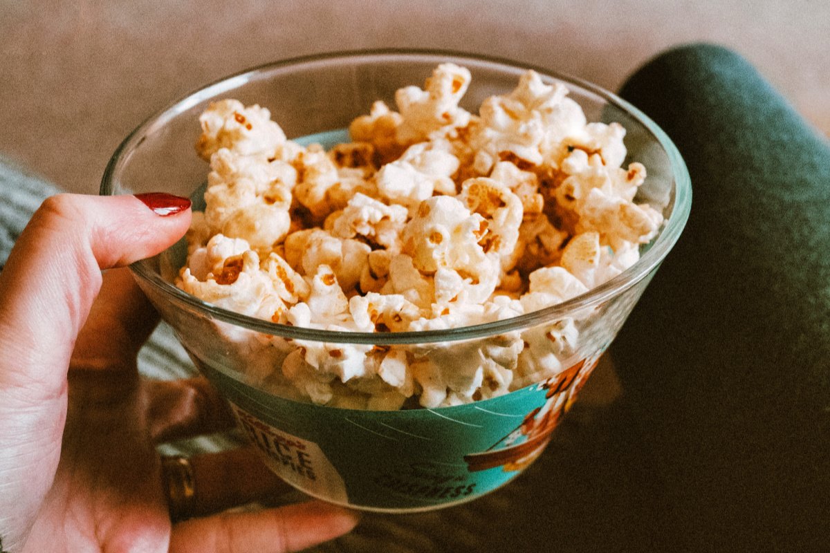 Sweet and Savory Popcorn Topping Ideas - spiced popcorn in glass bowl held by womans hand