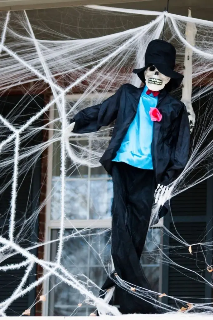 dressed up skeleton and fake spiderwebs in front of house