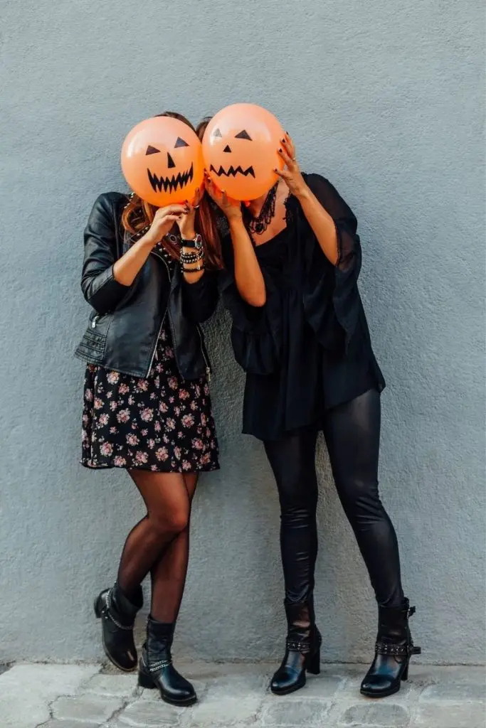 Teen girls wearing black and holding jack o lantern balloons - halloween costumes for teens