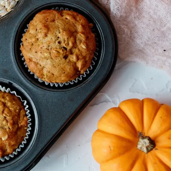 Pumpkin Oatmeal Muffins in muffin pan with mini pumpkin