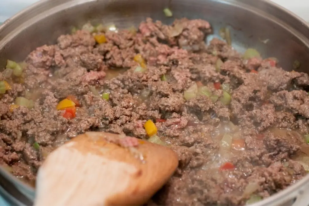Cooking ground beef with peppers and onions in frying pan