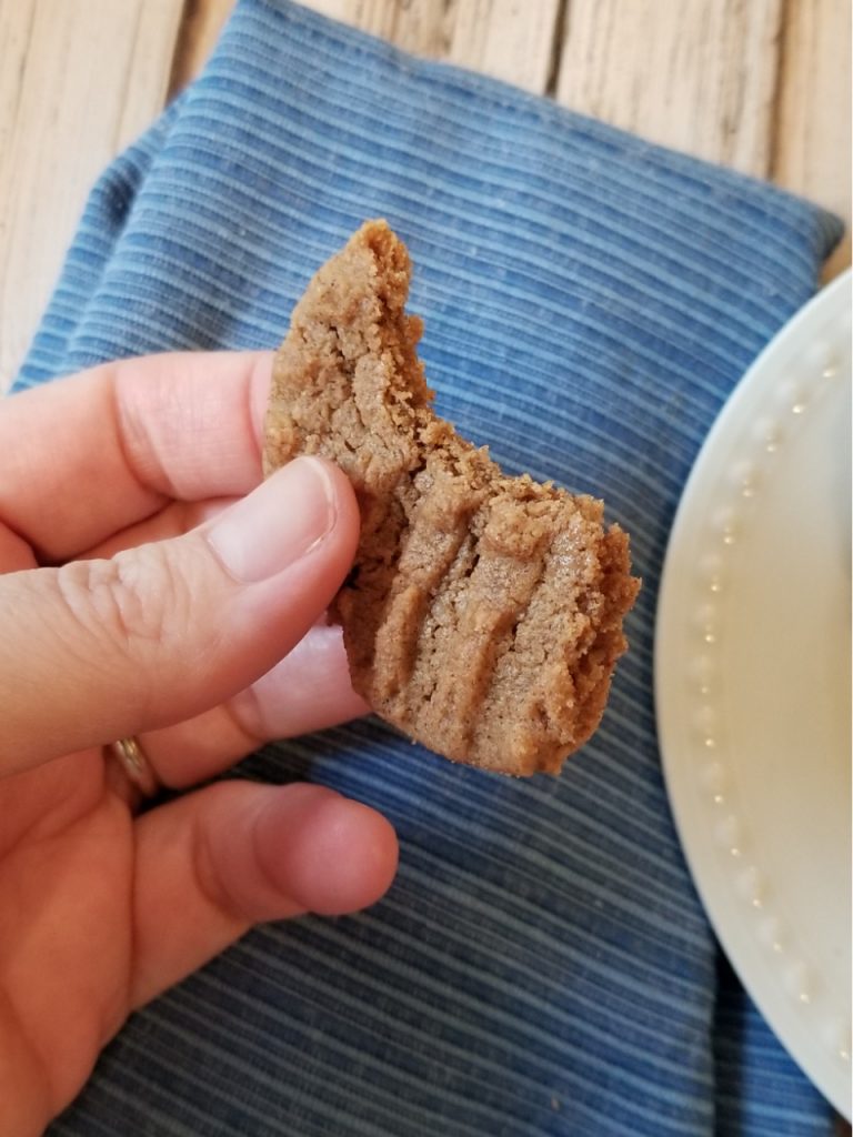 A finished cookie held up with a bite out of it. 