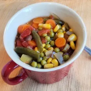 Vegetable soup in a red mug with handle