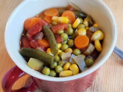 Vegetable soup in a red mug with handle