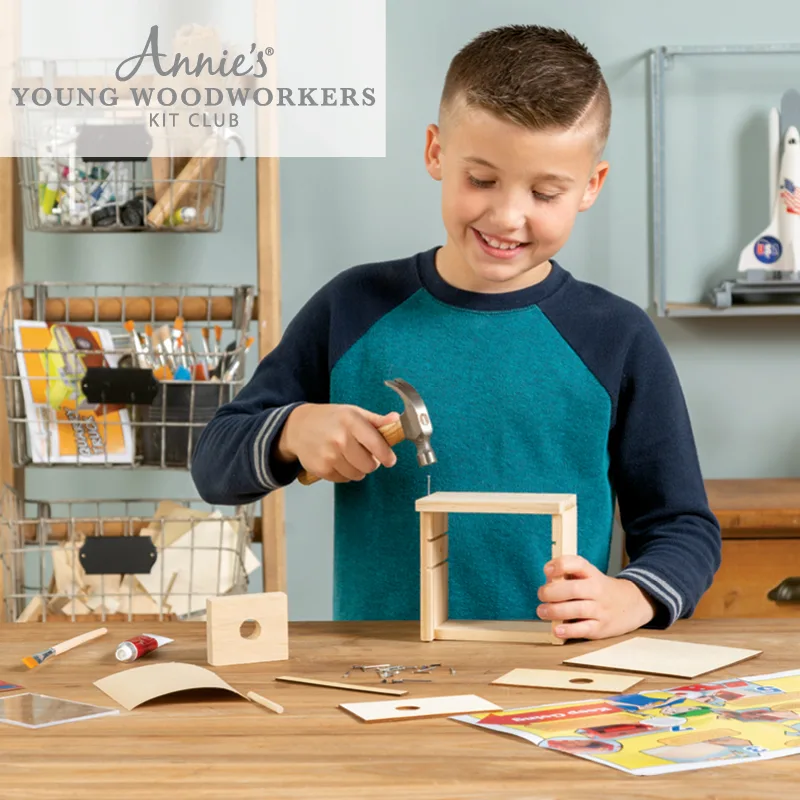 Boy using hammer to complete wood kit project