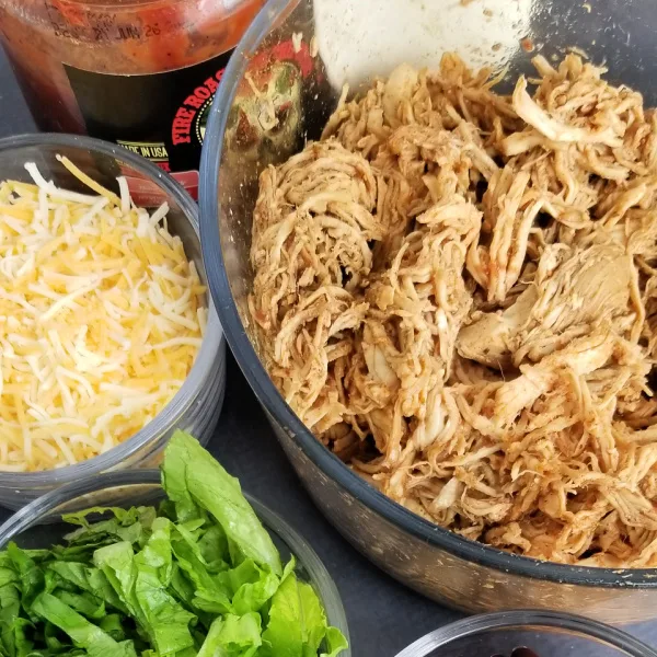 Shredded chicken taco meat with shredded cheese and lettuce in bowls - beginner slow cooker meals