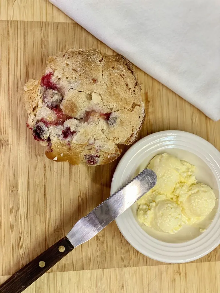 Breakfast muffin with butter and spreader on wooden table - must haves for baking muffins