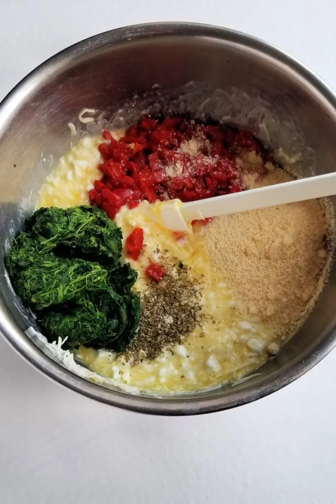 Eggs spinach red pepper cottage cheese and parmesan in stainless steel bowl with white spatula
