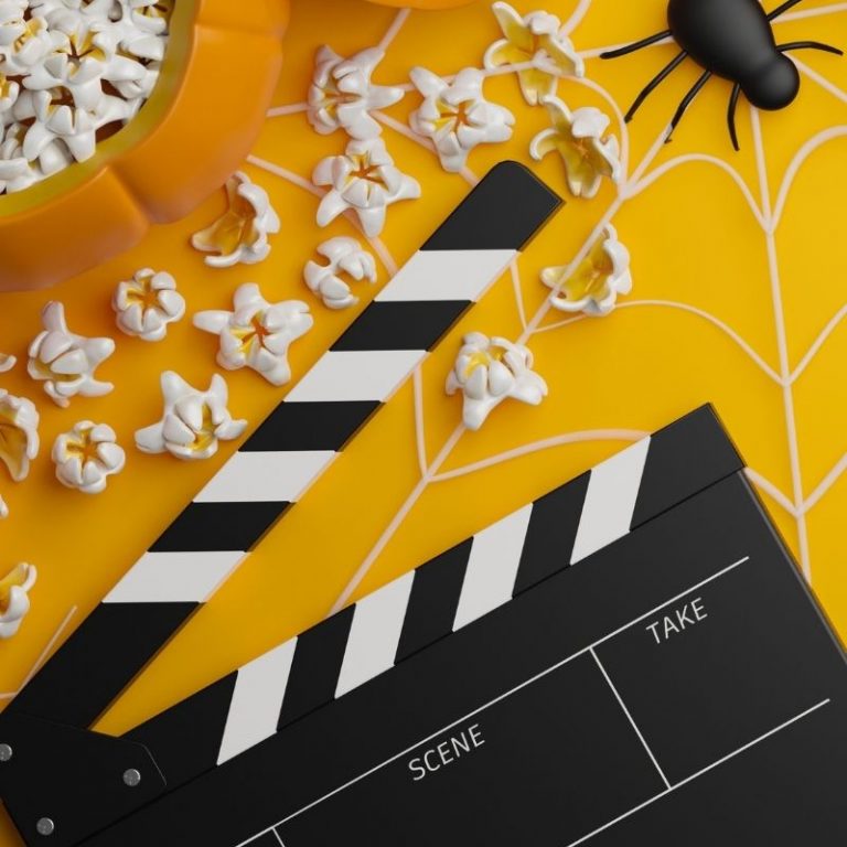 movie clapboard with popcorn and spider on orange background