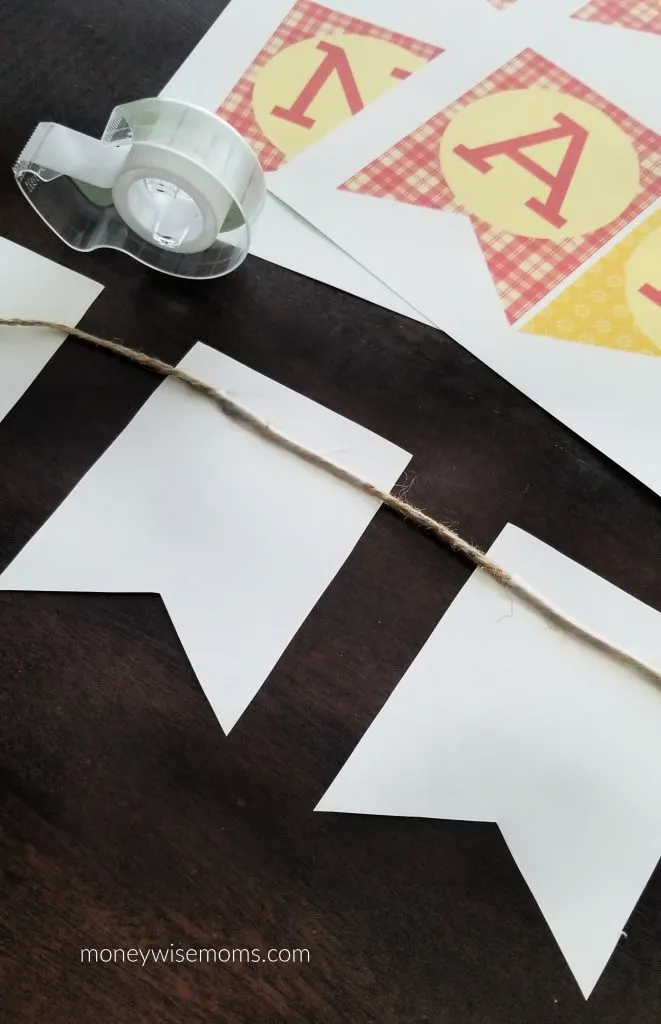 taping twine to back of Happy Thanksgiving bunting flags on dark wood table