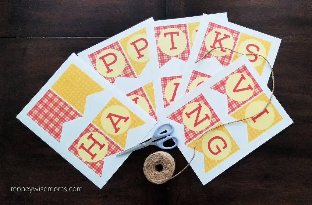 Happy Thanksgiving bunting printed out with scissors and jute twine on dark wood table