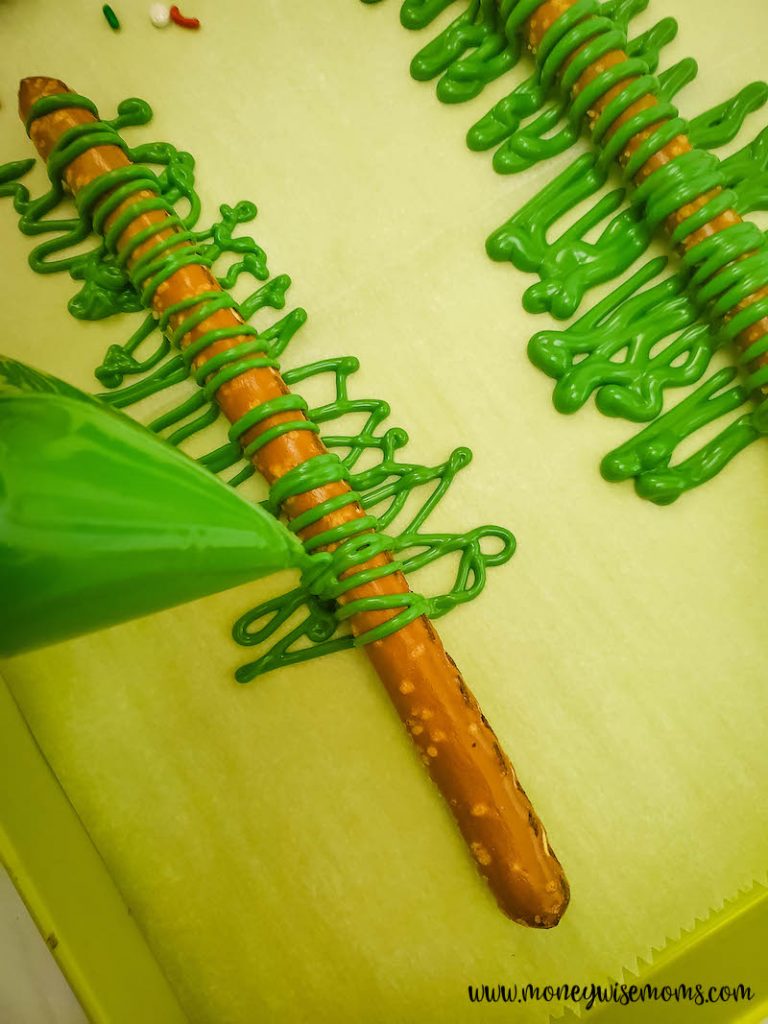 piping the candy onto the pretzel rods