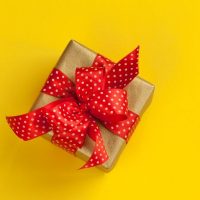 brown gift with red ribbon on yellow background