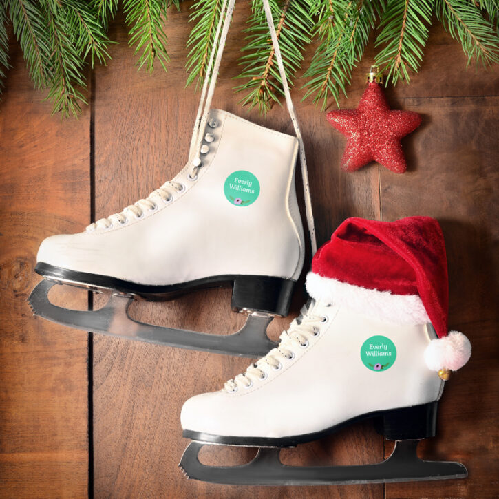 Ice skates hanging on wood wall with Christmas decor - NameBubbles labels