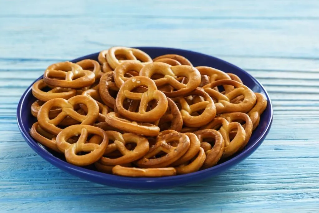 Plain unsalted pretzel twists in blue bowl on blue wooden surface - homemade seasoned pretzel recipes