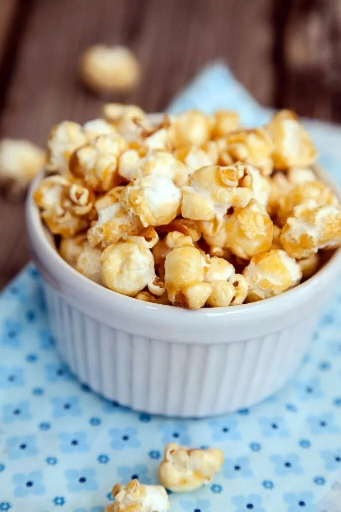 caramel popcorn in white ramekin on blue tray