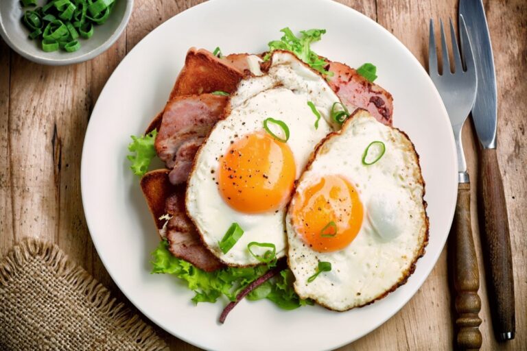 Over easy eggs with ham and toast on white plate