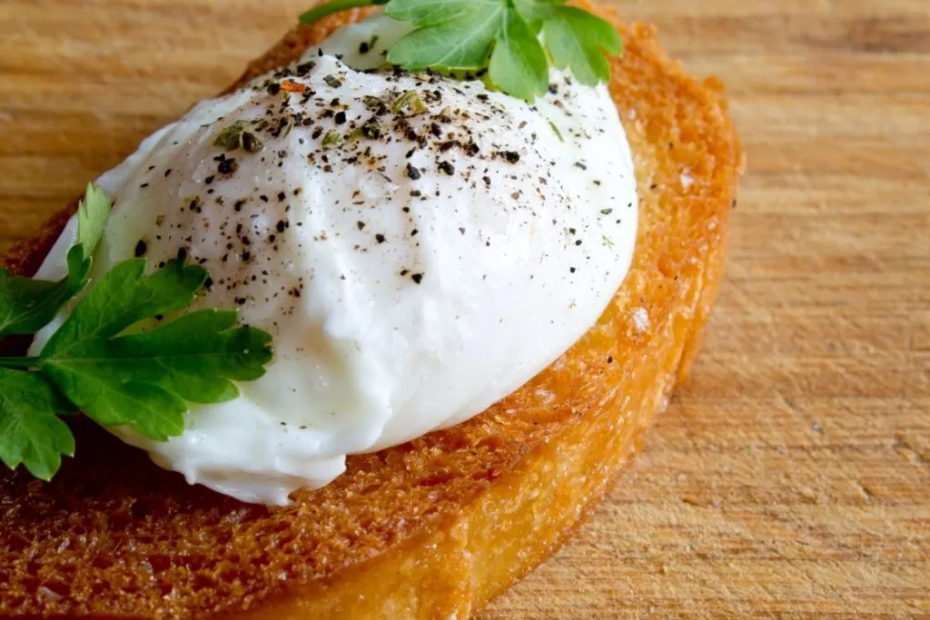 Poached egg and parsley on toast on wooden table