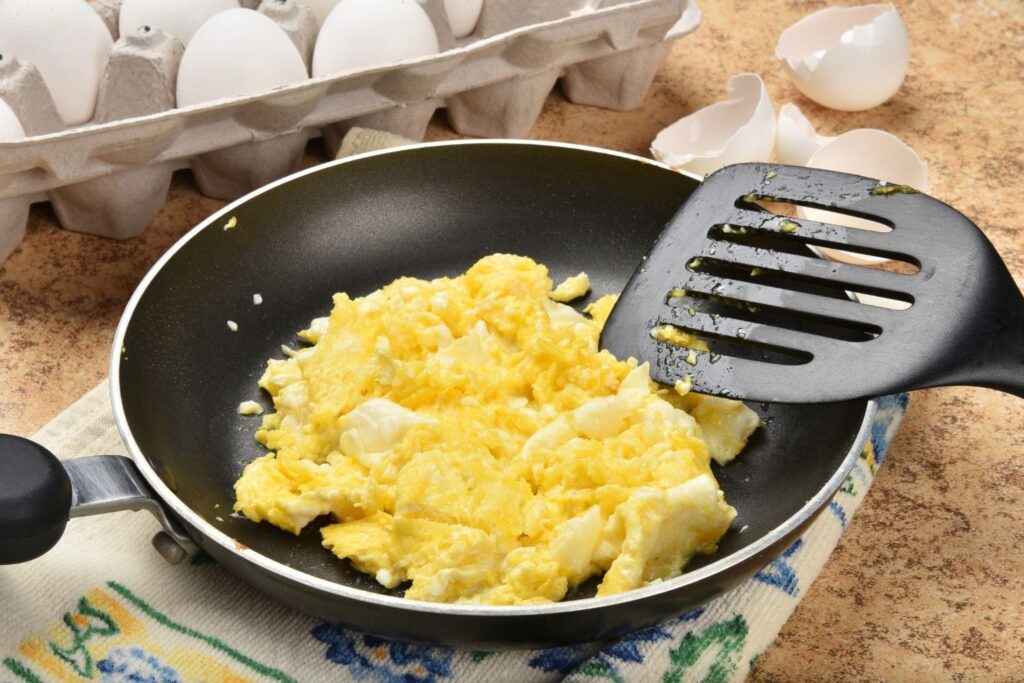 Scrambled eggs in frying pan with spatula