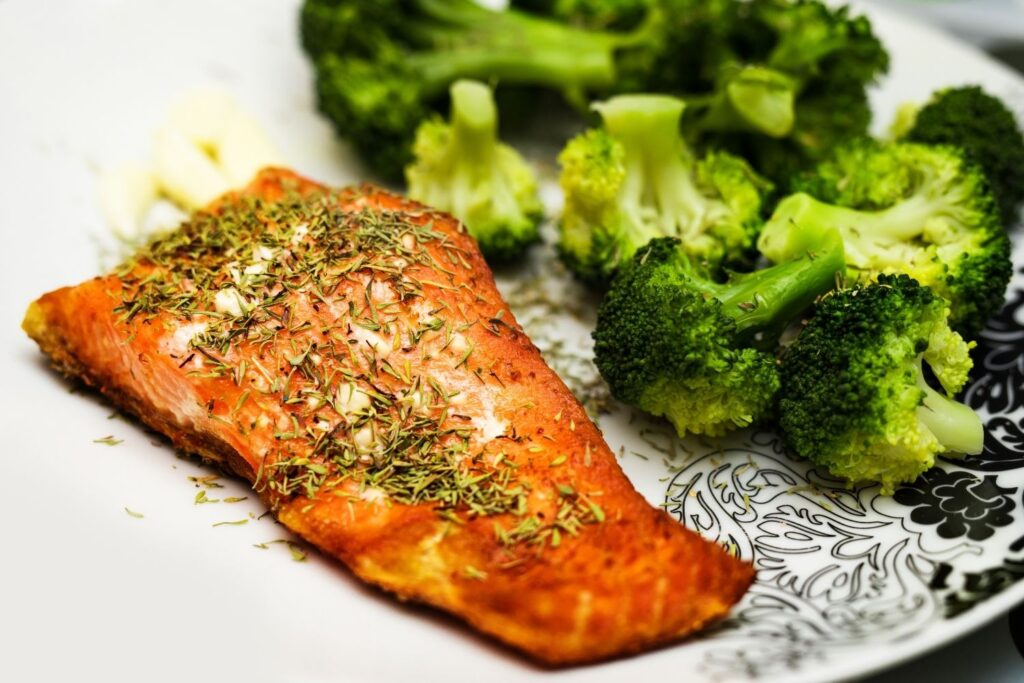 cooked salmon fillet with spices and broccoli on white plate