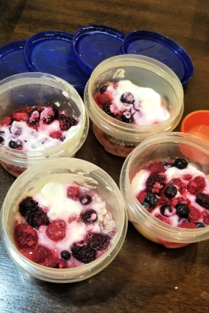 Preparing overnight oats with yogurt and frozen berries in ziploc containers