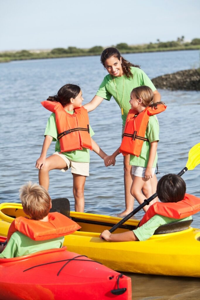Camp counselor with kids and kayaks on dock