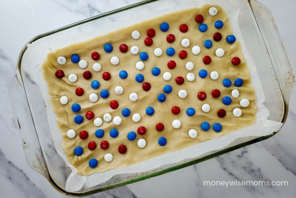 M&Ms pressed into raw cookie dough in baking dish