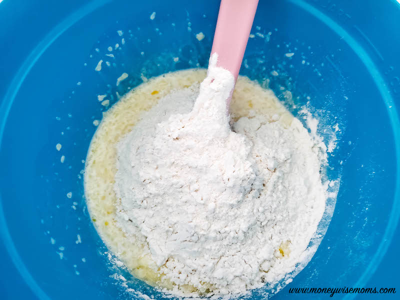 adding flour to the wet ingredients in mixing bowl