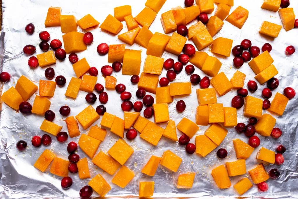 chunks of sweet potato and fresh cranberries spread into one layer on baking sheet