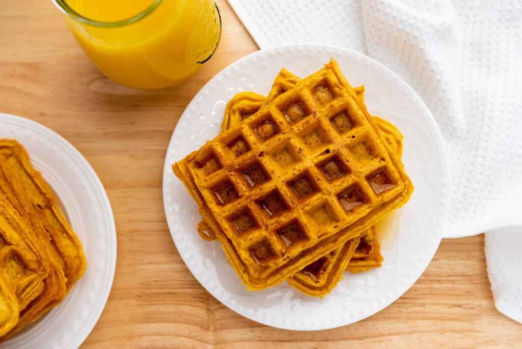 pumpkin waffles on white plate on wooden table