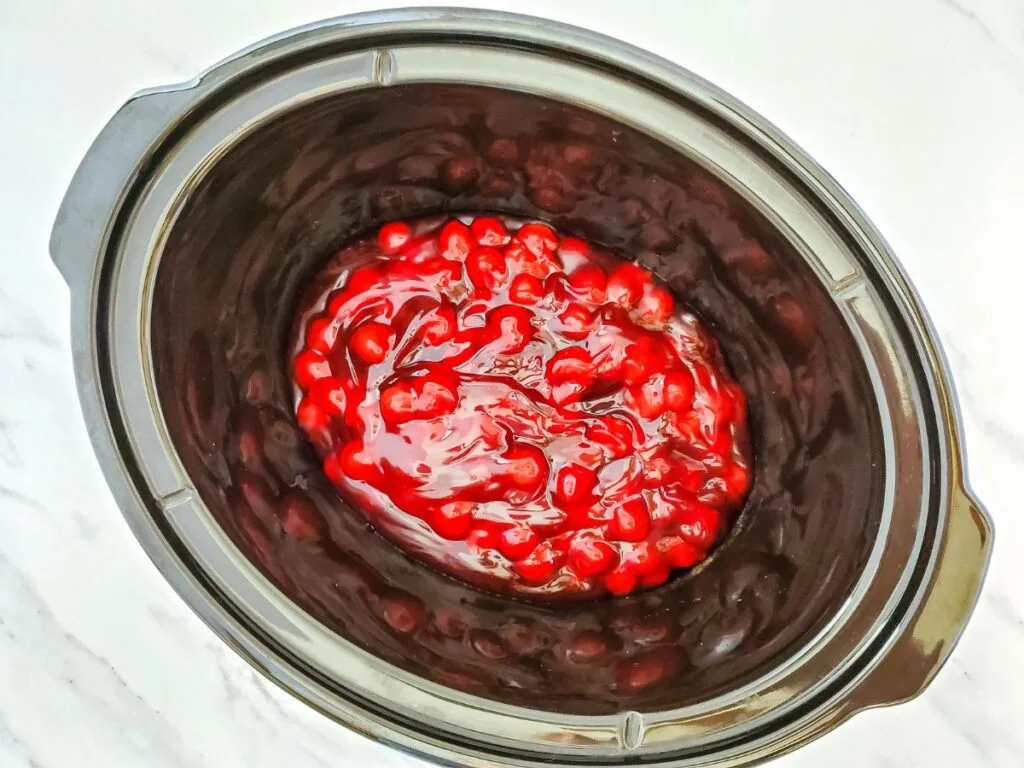 cherry pie filling in bottom of black slow cooker