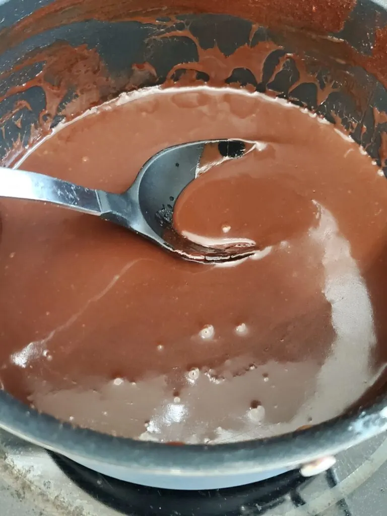 melted chocolate chips in heavy cream with metal spoon