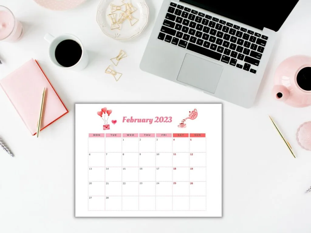 horizontal February calendar on desktop with pin accessories and laptop computer