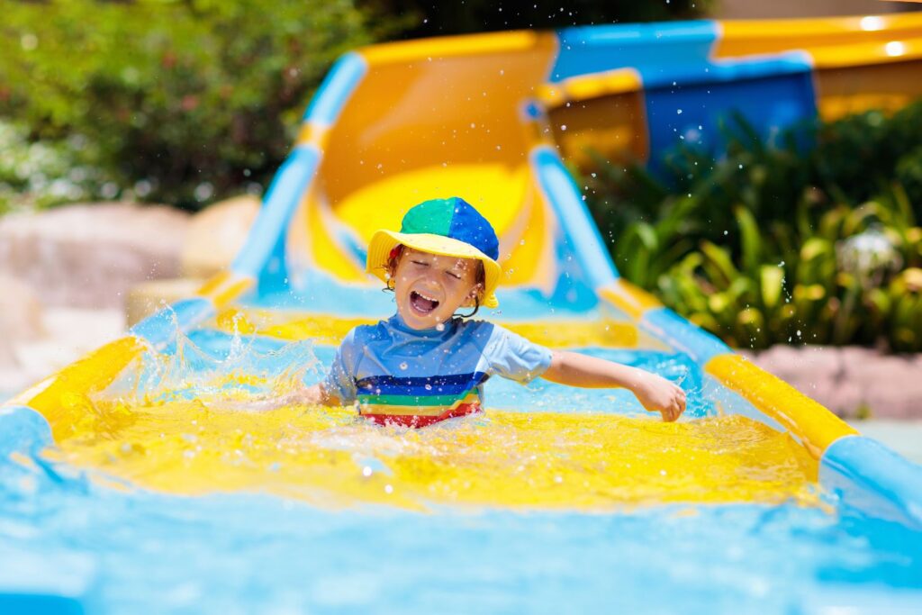 boy at bottom of yellow and blue waterslide