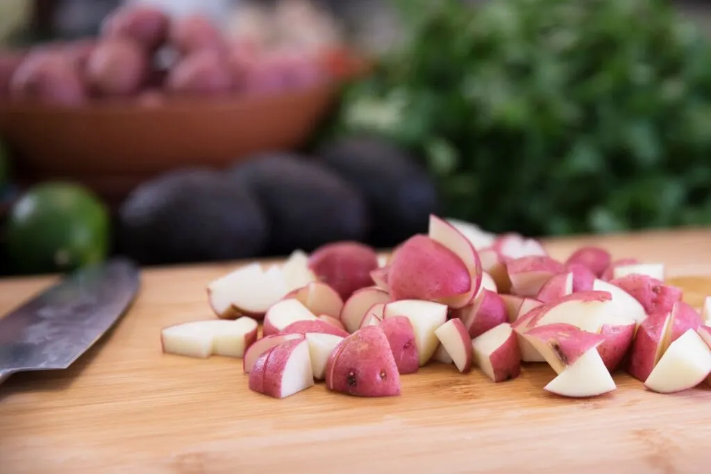 cutting red potatoes on wooden cutting board
