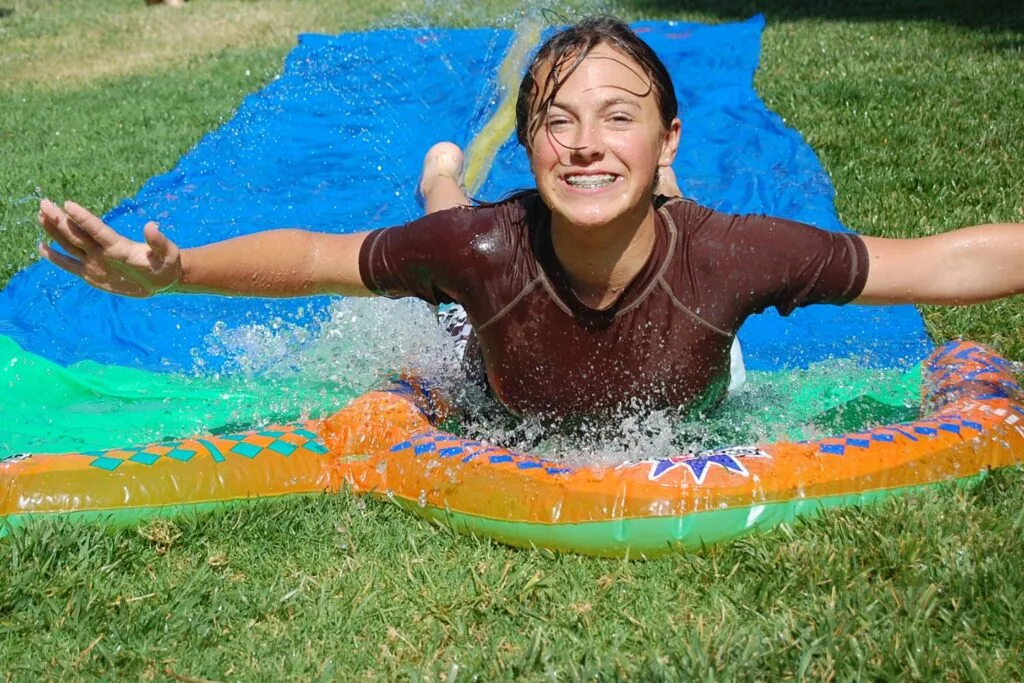 girl on slip and slide on backyard grass