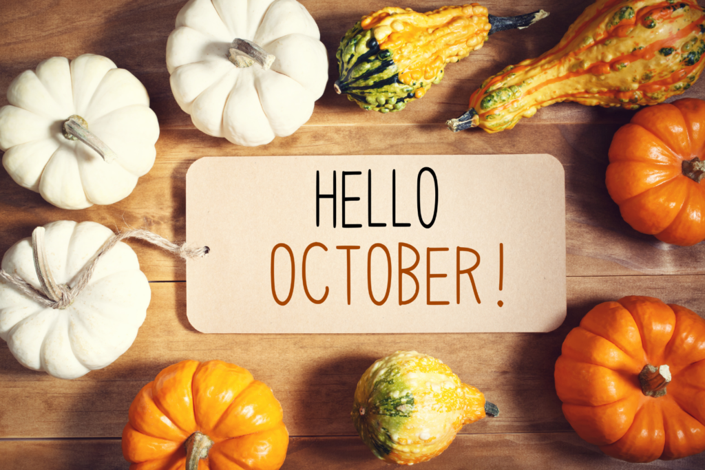 Hello October tag on wooden table with pumpkins and gourds