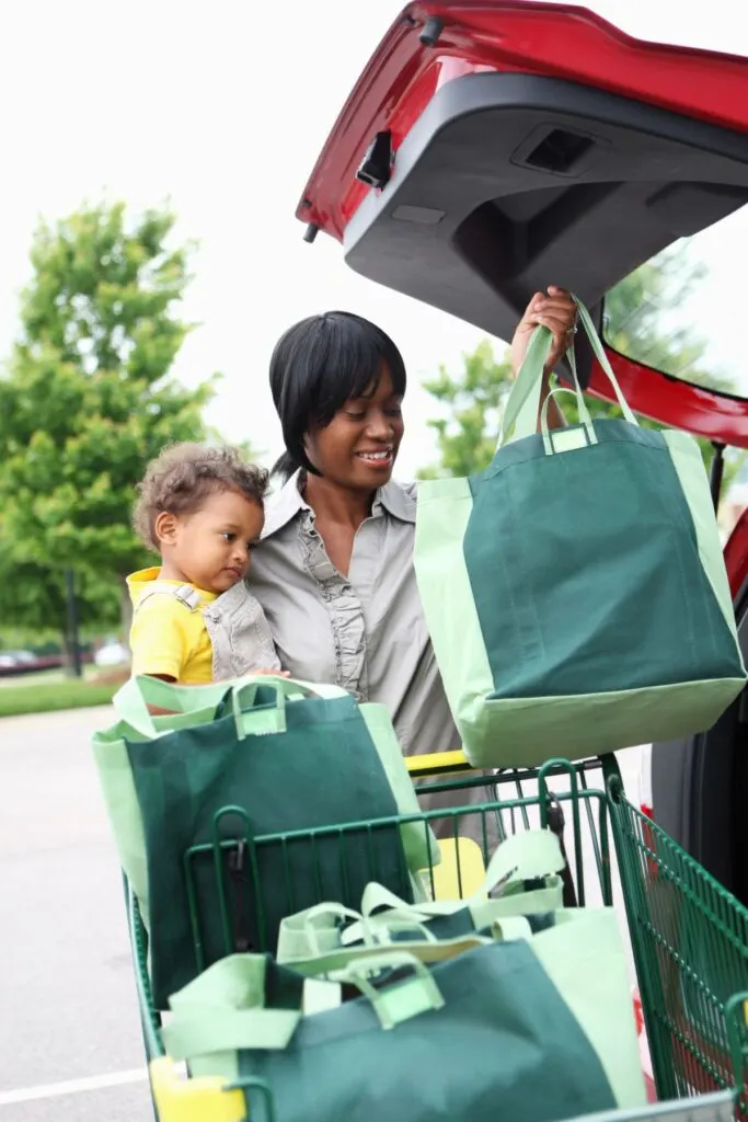 mom with baby and grocery shopping bags at trunk of car