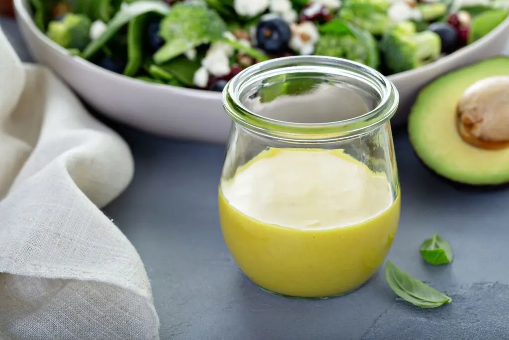 mustard vinaigrette in clear glass jar with avocado