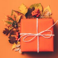 orange square gift with fall leaves on orange background