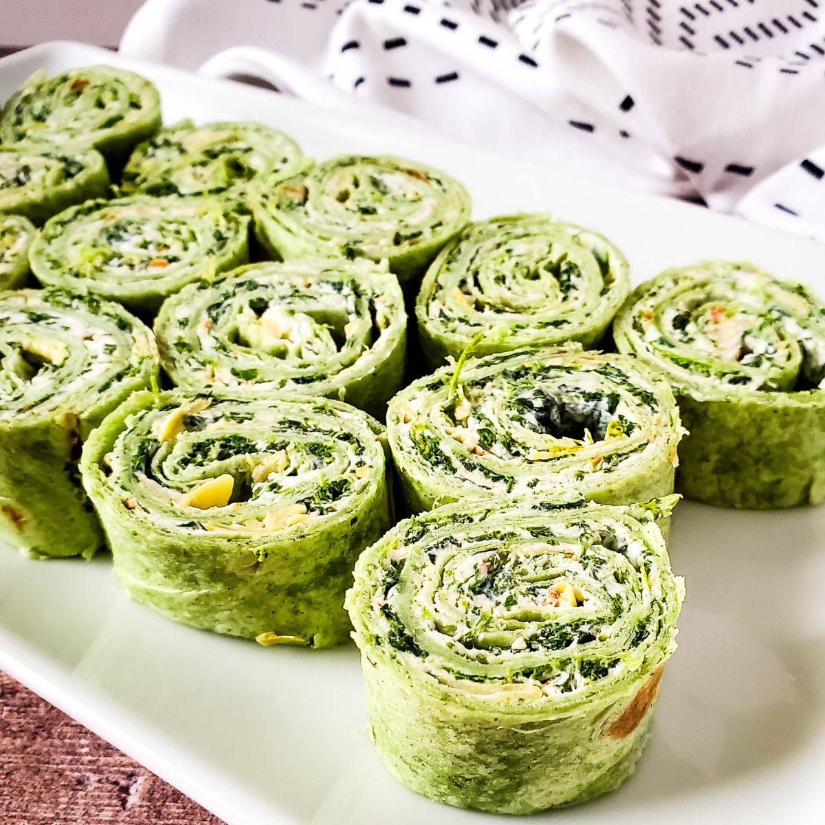 spinach artichoke pinwheels on white tray