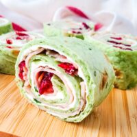 close up of cranberry turkey pinwheel appetizer on wooden board
