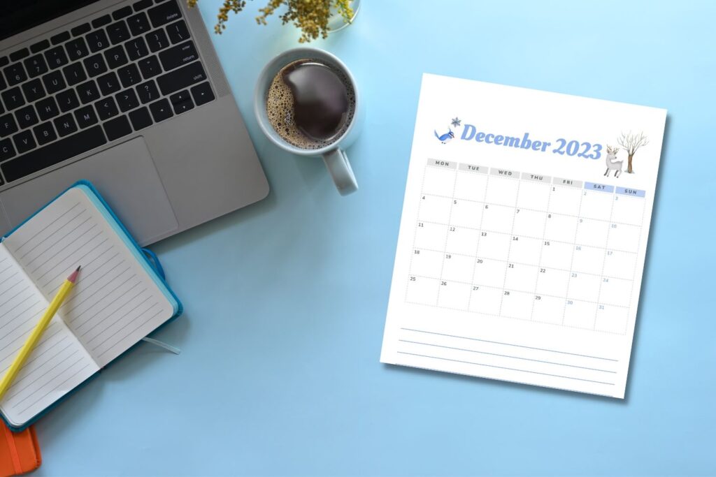 printed December calendar on blue desk with laptop notebook and coffee