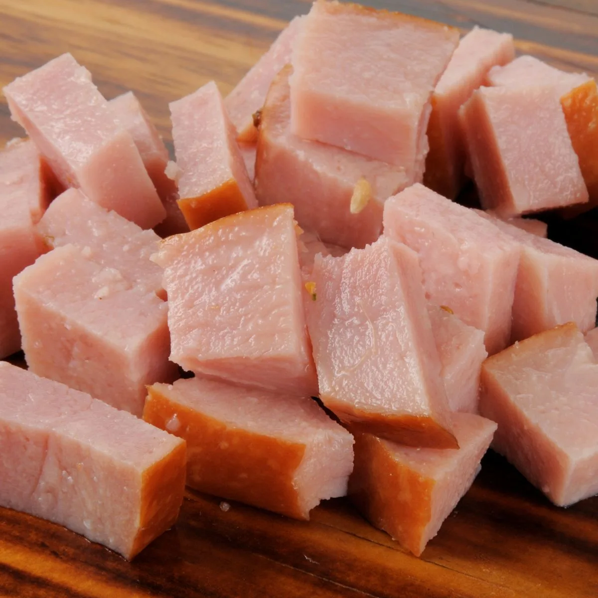 Cubed leftover ham on wooden cutting board