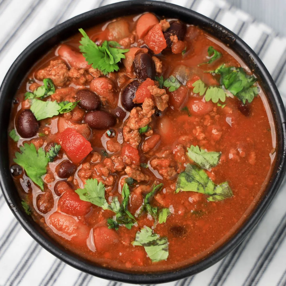 serving of ground beef chili in black bowl